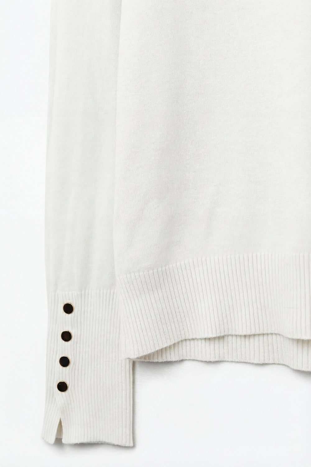 Pull à col roulé blanc avec boutons dorés sur la manchette