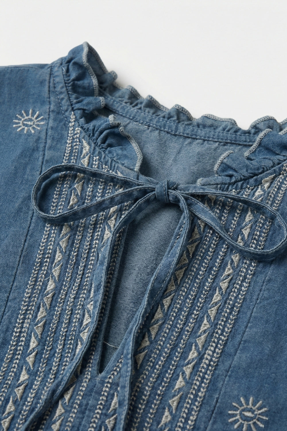Tunique en denim brodée avec encolure à volants et nouée sur le devant