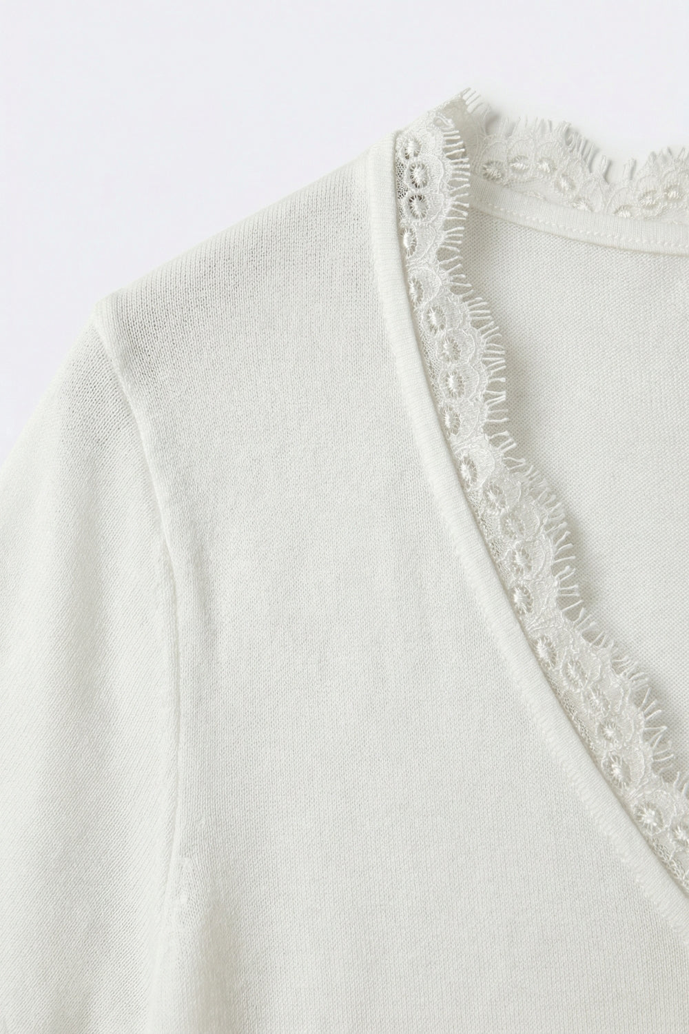 Pull en maille fine et douce avec col en V et bordures en dentelle en blanc