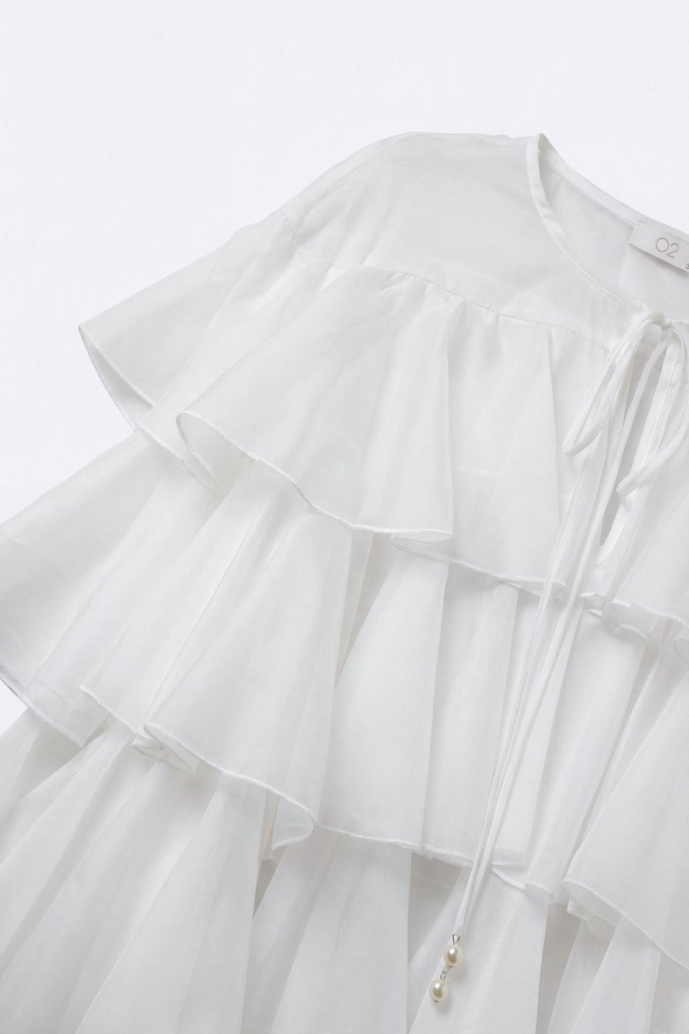 Blouse blanche à volants superposés avec col à nouer