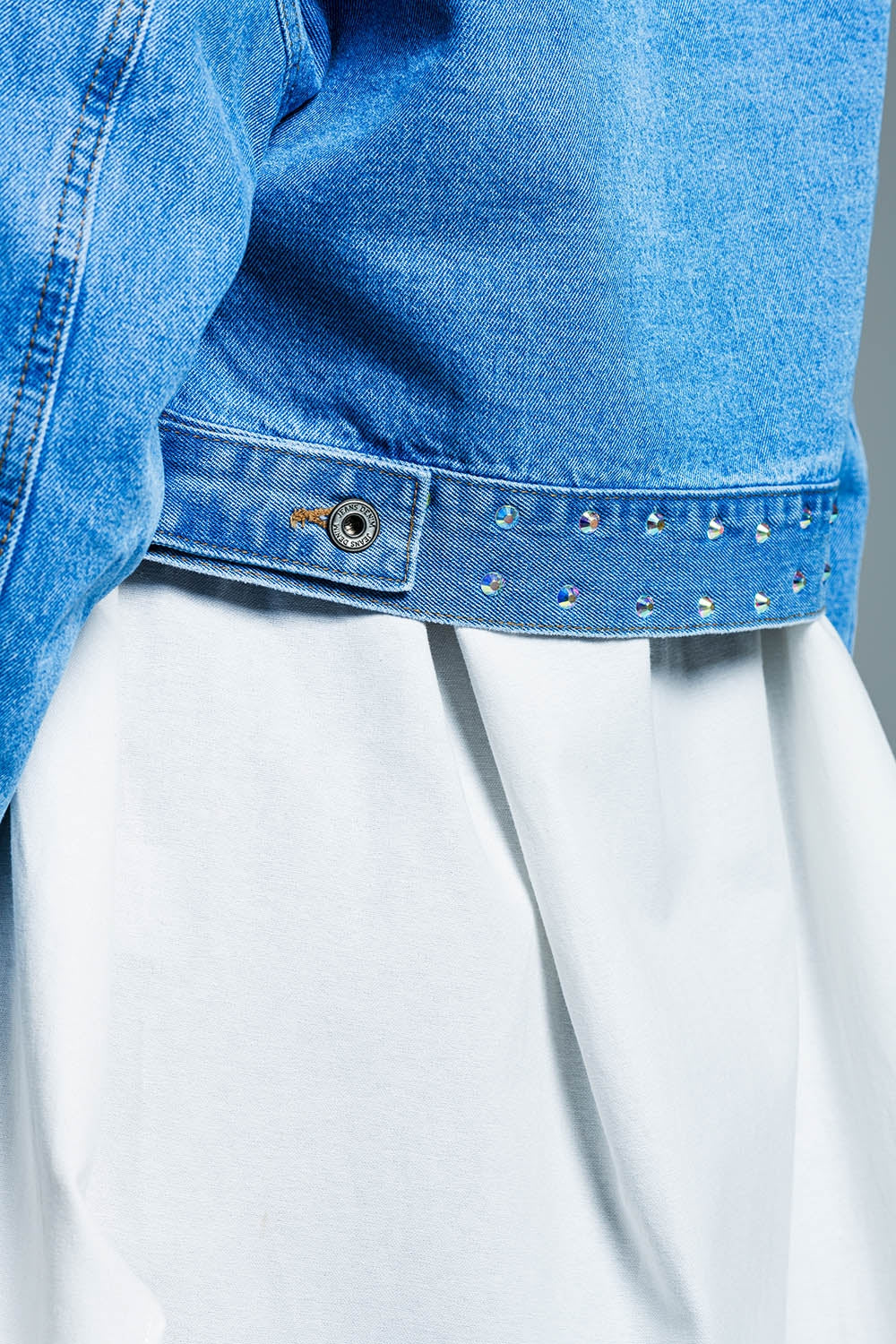 Veste croisée en denim bleu avec clous et poches sur la poitrine
