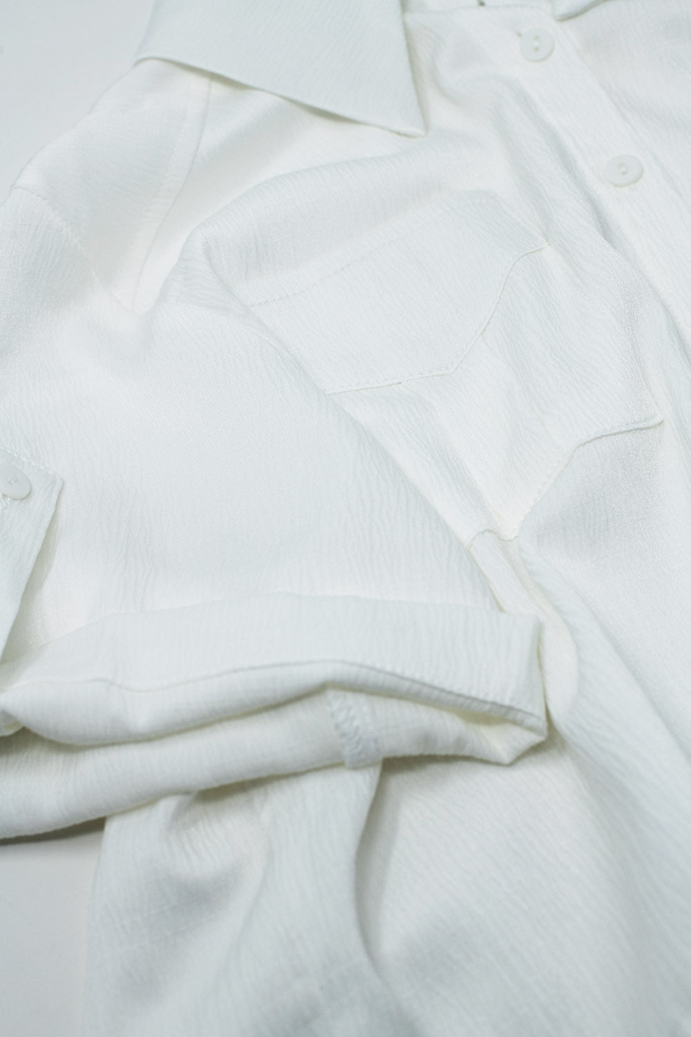 Chemisier court blanc satin avec poches sur la poitrine et cordons de serrage au bas