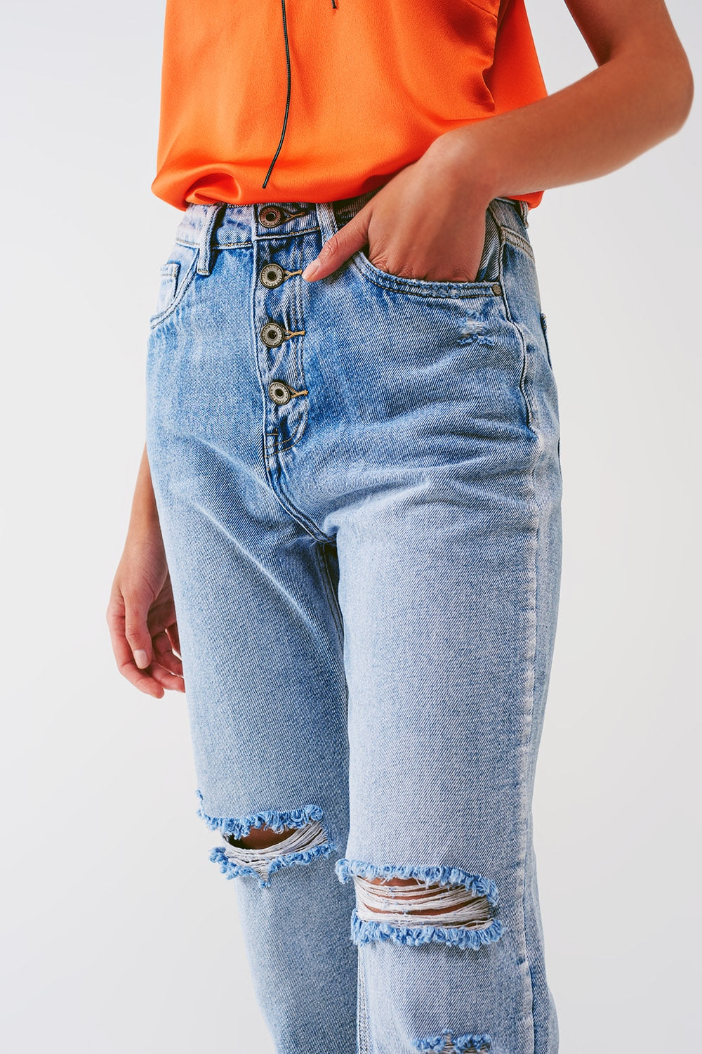 Jean à jambe droite avec boutons apparents et genoux déchirés en délavage léger