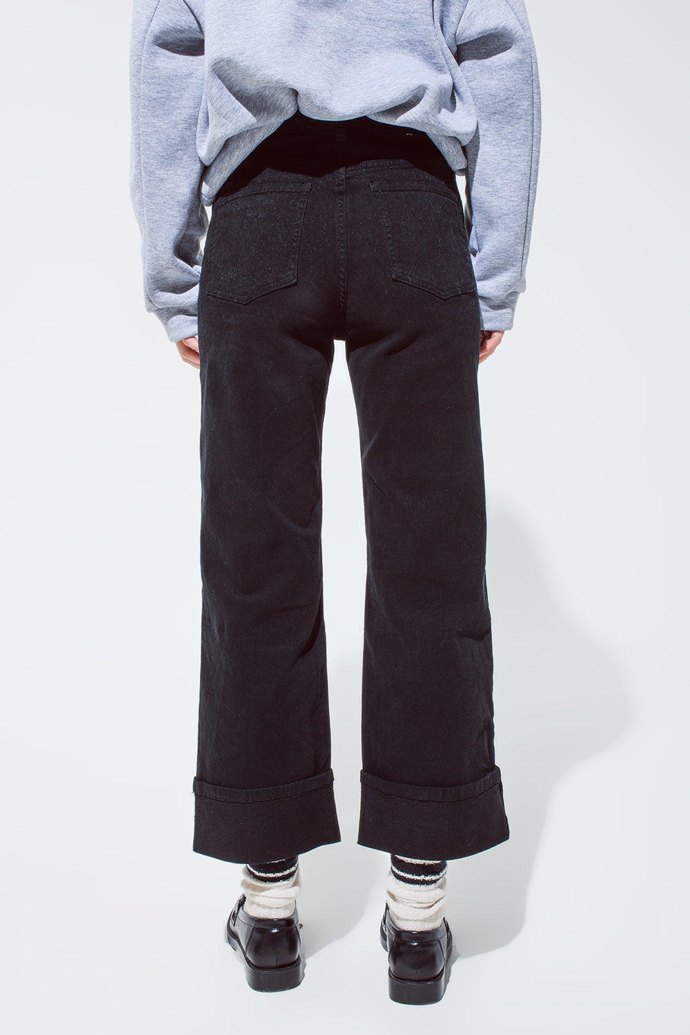Jean droit noir avec les jambes repliées