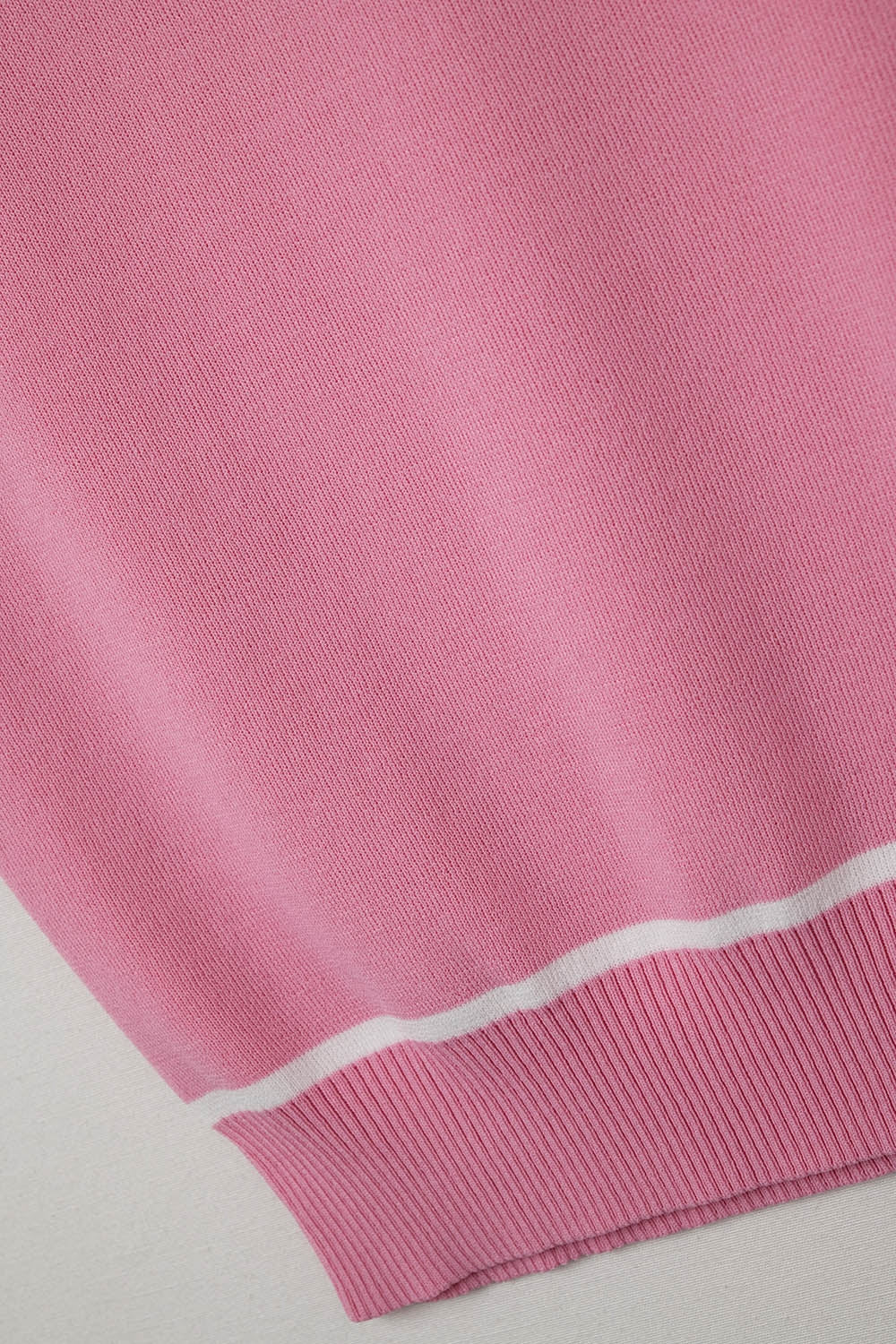 Pull sans manches en rose avec des lignes blanches en détail