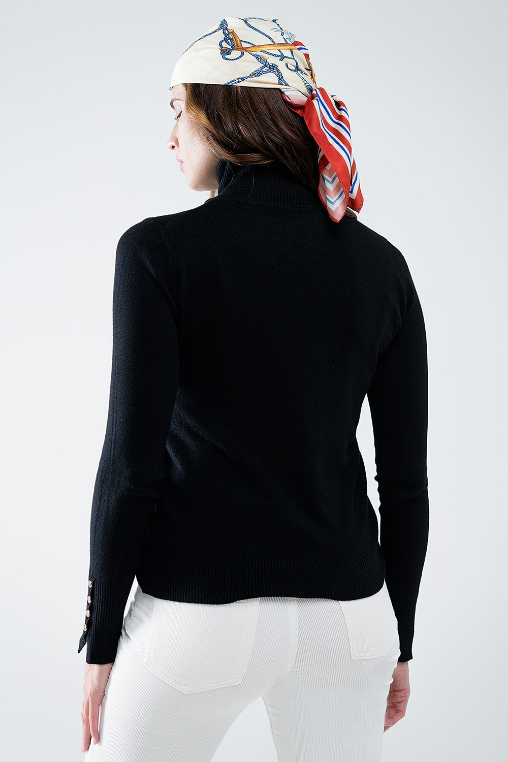 Pull à col roulé noir avec boutons dorés sur le poignet