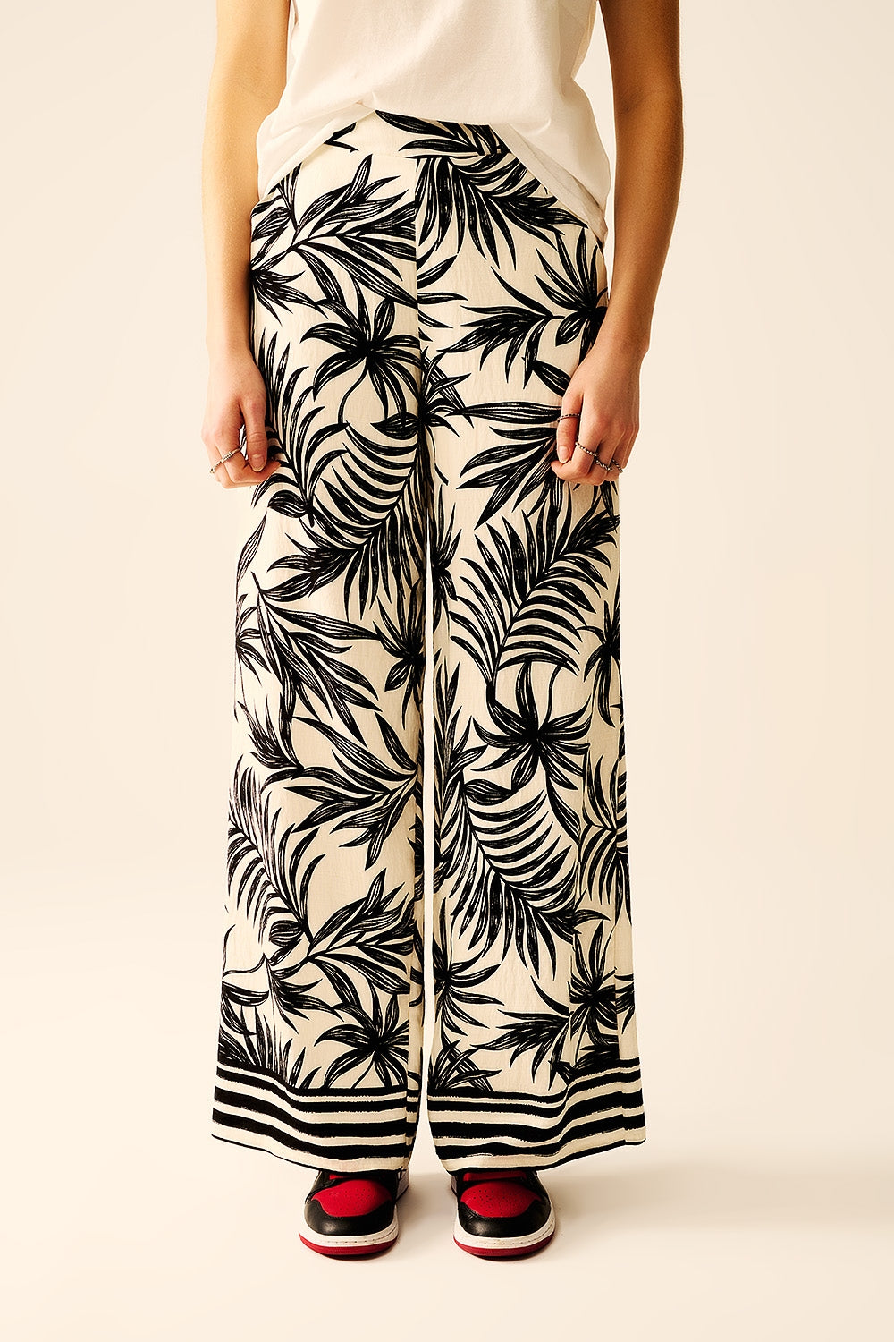 Pantalon à jambes larges en blanc avec détails floraux en noir
