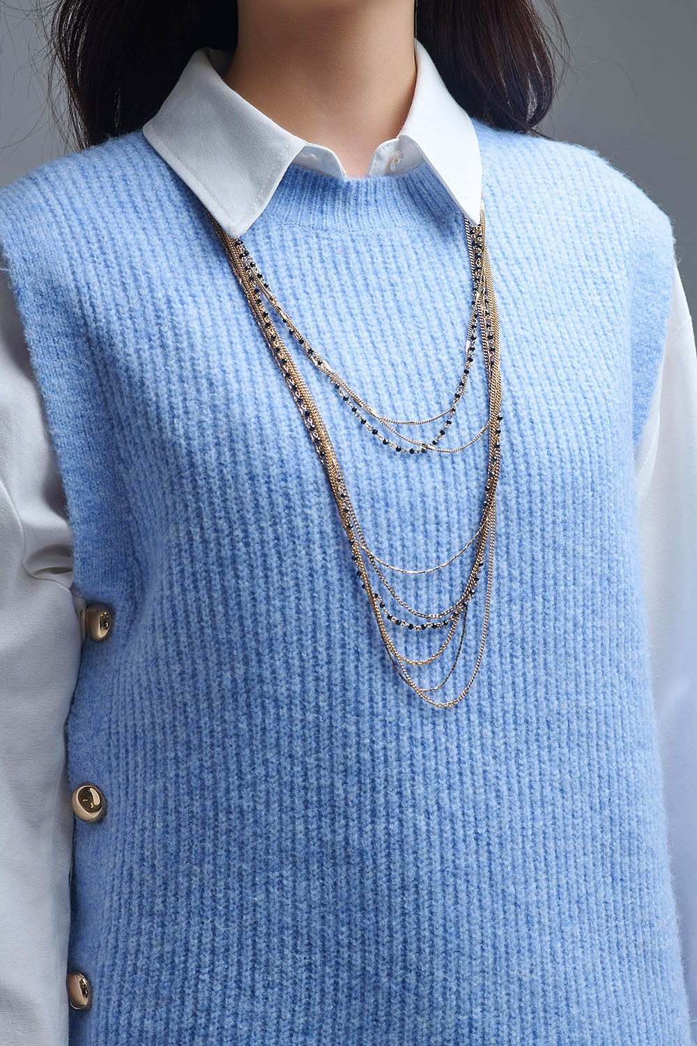 Pull bleu sans manches avec boutons dorés sur le côté