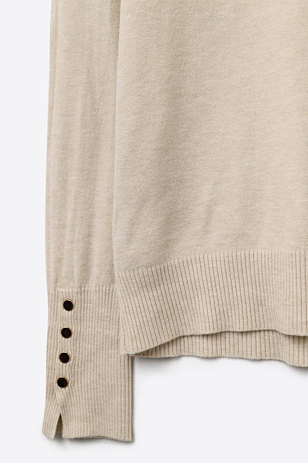 pull à col roulé beige avec boutons dorés sur la manchette