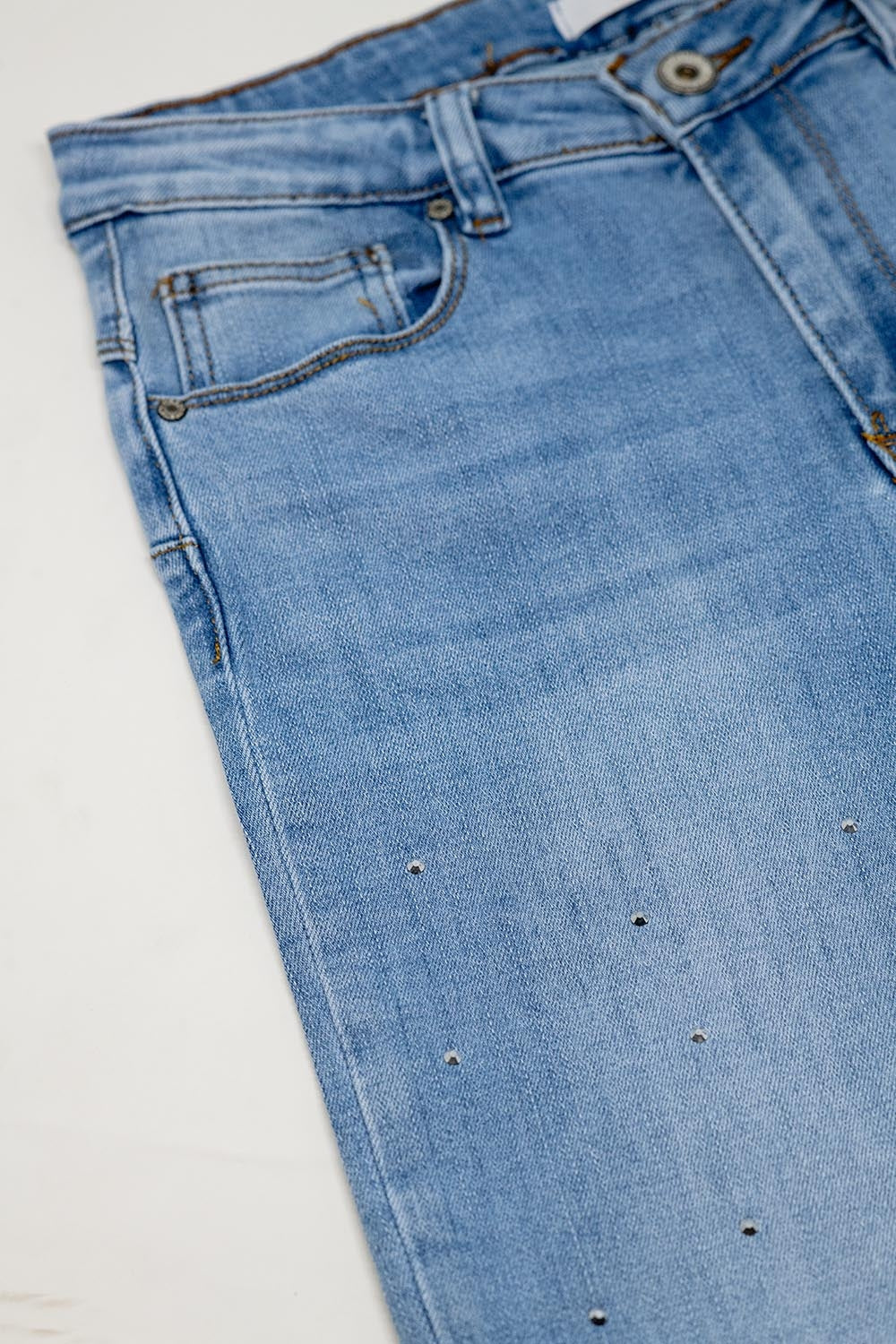 Jean à cinq poches avec détails brillants et fermeture sur le devant