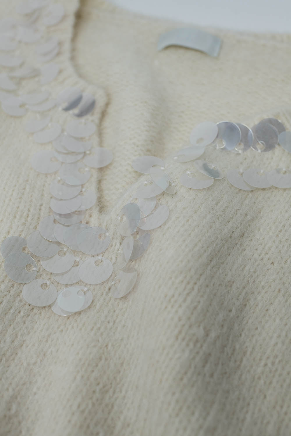 Pull à col en V crème avec détails en sequins