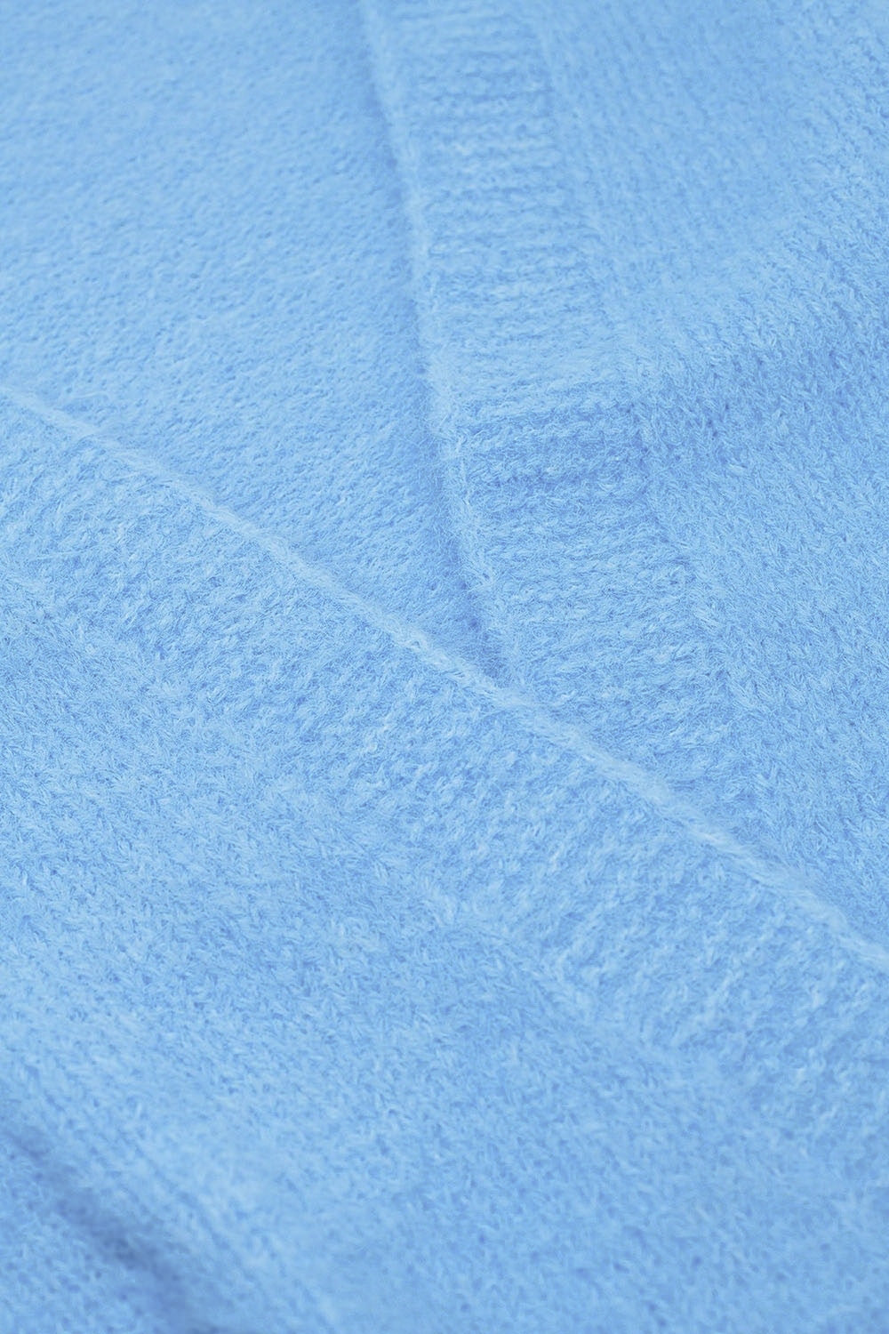 Cardigan ouvert décontracté en maille duveteuse bleu layette avec bords-côtes au niveau des manches et des poignets.