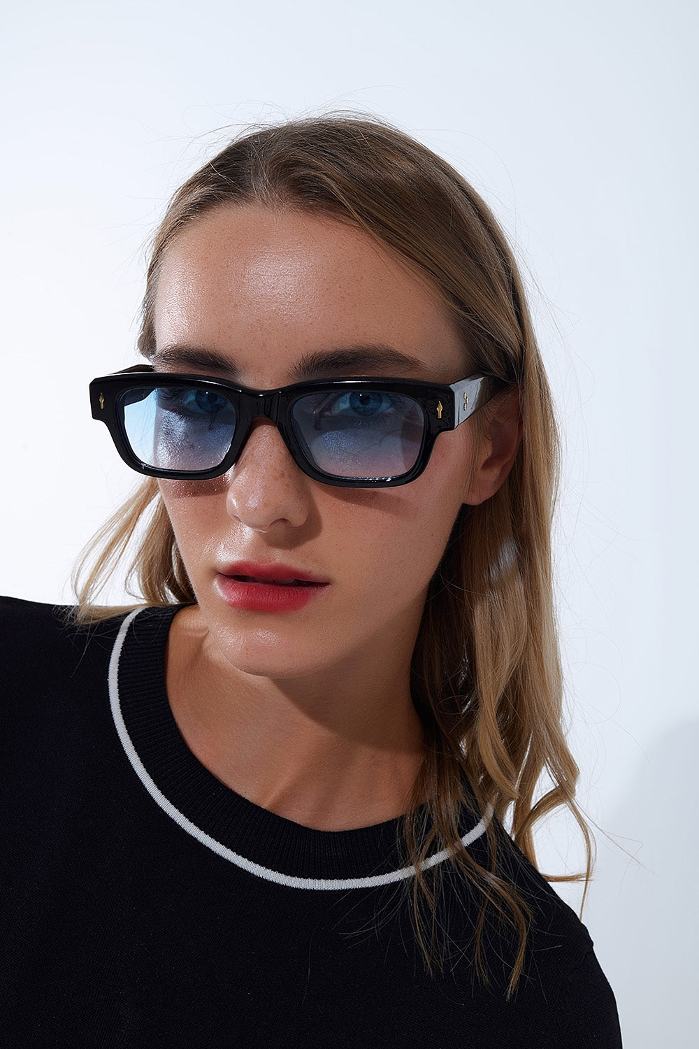 Lunettes de soleil noires à monture ovale avec détails dorés et verre bleu