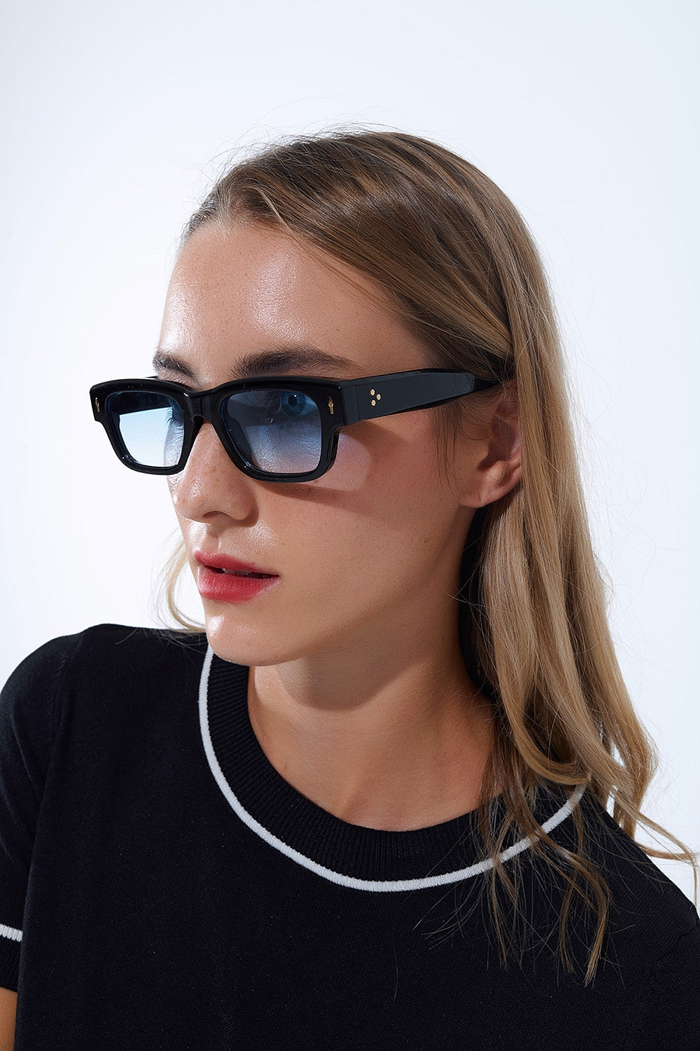 Lunettes de soleil noires à monture ovale avec détails dorés et verre bleu