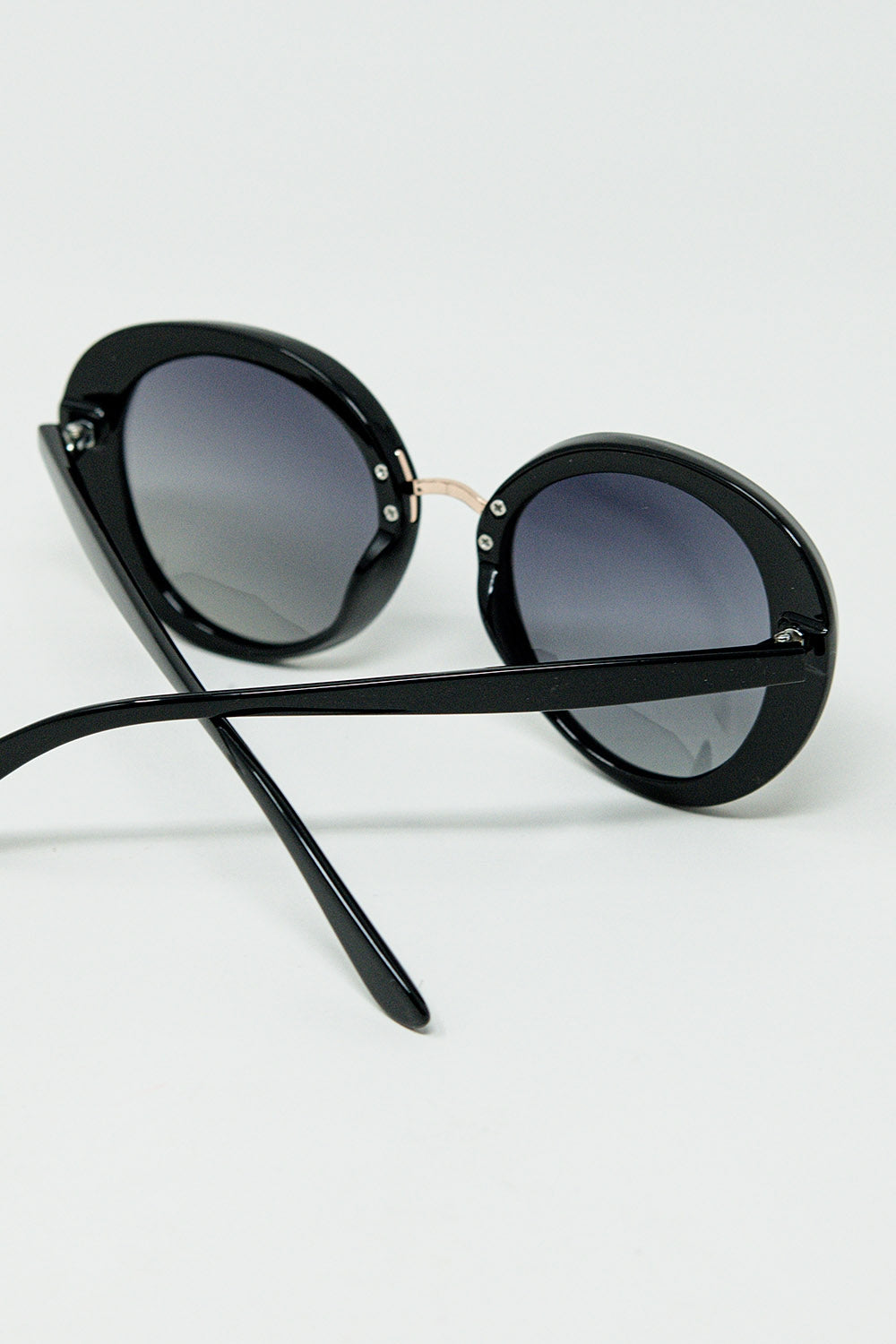 Lunettes de soleil noires de forme ovale avec détails en métal doré