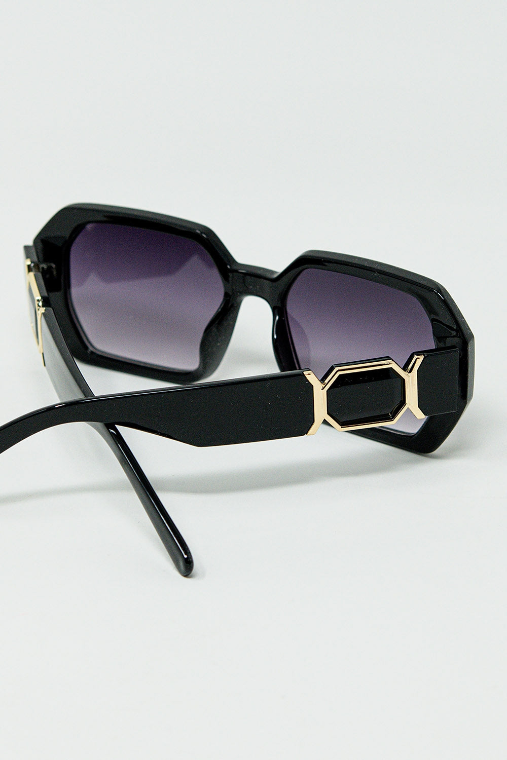 Lunettes de soleil noires en forme de losange et détails dorés