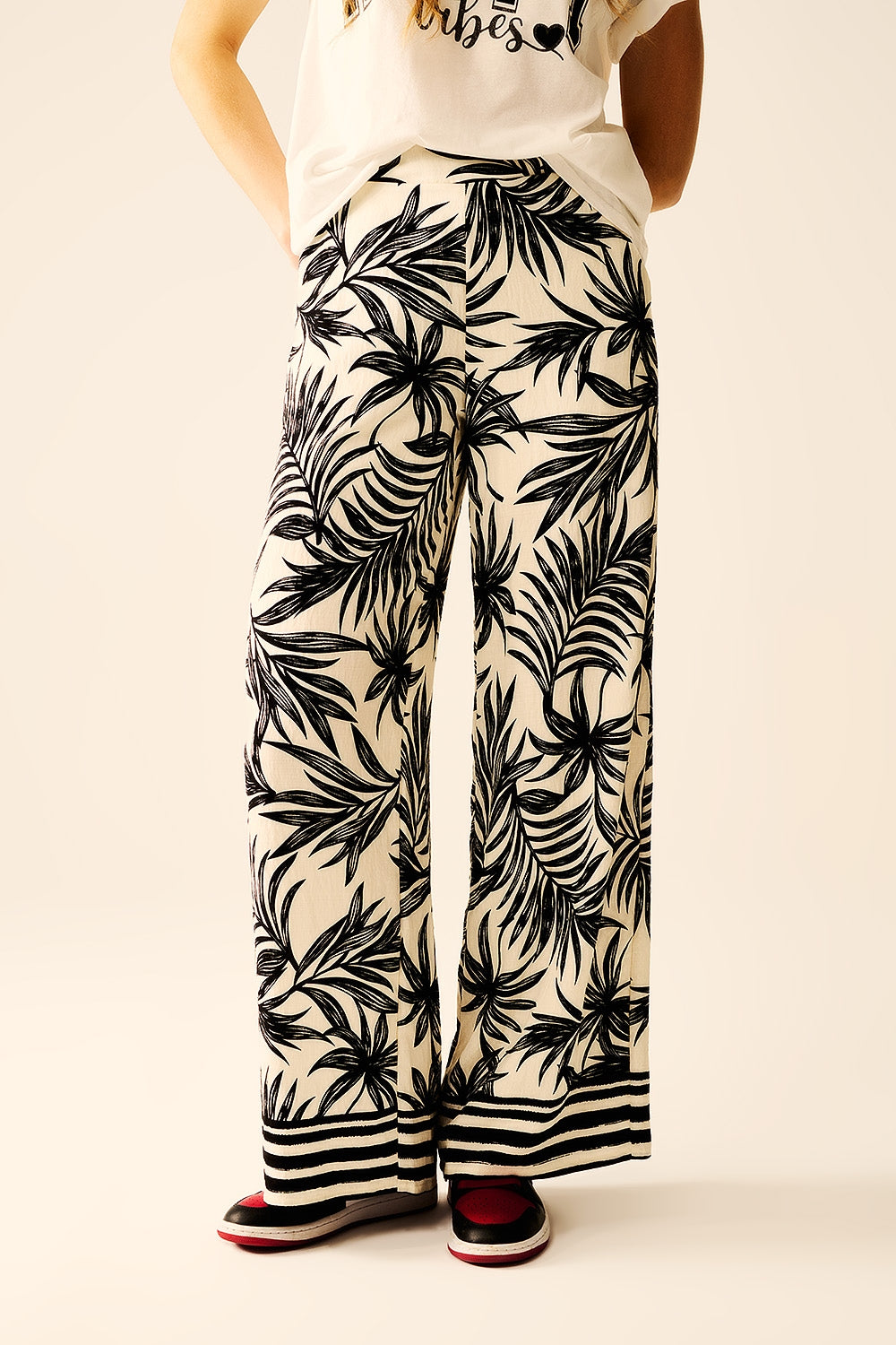 Pantalon à jambes larges en blanc avec détails floraux en noir